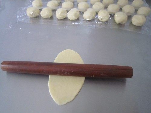 咬一口酥软掉渣的蛋黄酥,用手按扁,用擀面杖由中间分别向上向下擀开