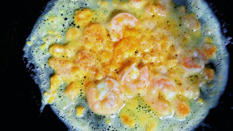 金沙玉米饭,待油烧热后,倒入蛋黄泥和虾仁,转小火,轻轻翻炒,直至蛋黄泥炒出白沫和香味。
