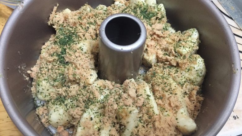 肉松海苔手撕面包 直接法,将面块叠放在一起竖着放入中空模具中,再撒上些肉松和少量海苔粉