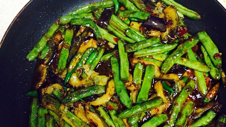 四季豆烧茄子,四季豆煮熟以后倒入青椒和茄子,小火翻炒