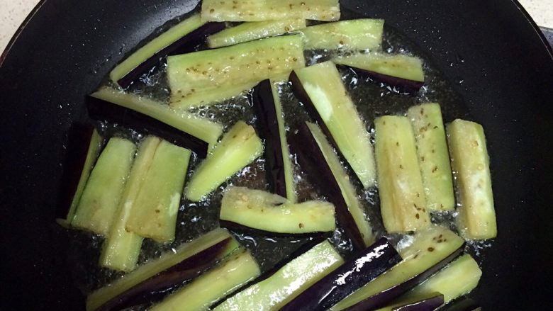 四季豆烧茄子,在锅中加一小碗油,待油热以后把茄子倒入,等茄子炸软以后捞出。倒出锅中一半的油,剩下一半