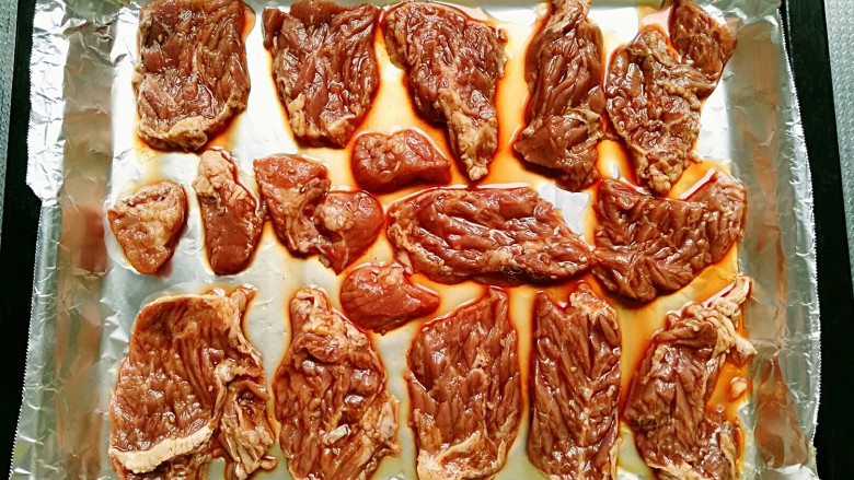 秘制烤牛肉披萨,将腌好的牛肉摆放在铺好锡纸的烤盘里,烤箱预热5分钟,上下火200度烤15分钟