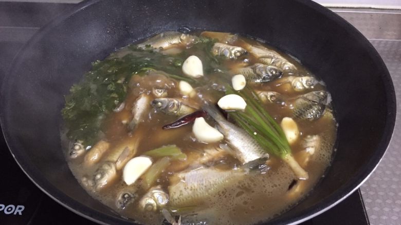 酥焖鲫鱼,放蒜,撒盐,继续小火炖20分钟