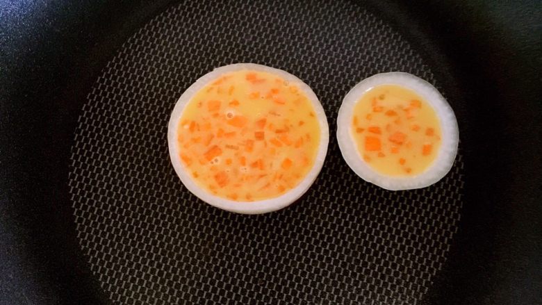 洋葱圈鸡蛋饼,勺入胡萝卜鸡蛋液,洋葱圈舀入的面糊9分满就行,因为鸡蛋会胀起来,全程小火煎熟即可
