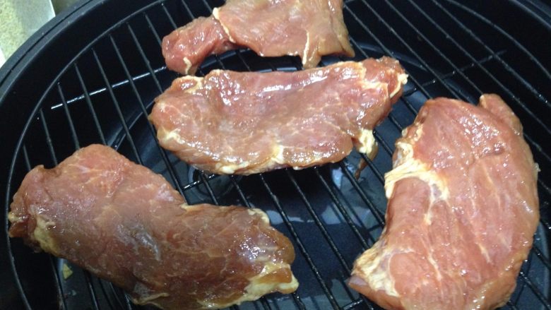 蜜汁叉烧肉,肉片取出恢复室温,放入烤架(烤架下面可以用一只等大的烤盘倒入少许水,用来盛接滴下来的油脂和酱汁,为了便于清理,还可以衬一层锡纸)