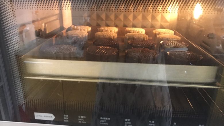广式巧克力莲蓉月饼,烤箱预热200度预热好,月饼表面喷水,要用喷雾器,不能直接朝着月饼喷,要喷在月饼上空让水雾慢慢掉下,然后放入烤箱200度6分钟后取出刷蛋液