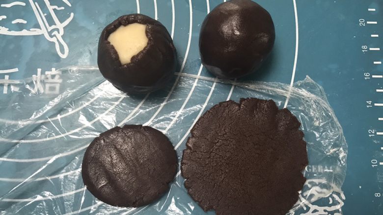 广式巧克力莲蓉月饼,取一个面团用手掌摁一下擀成圆形,包上莲蓉馅,用虎口慢慢收口