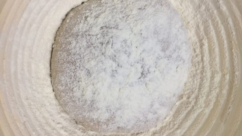 洛可可香蕉面包(水果种),将洛可可面团排气后收紧成圆形,放入发酵篮里,表面撒上手粉轻轻按压