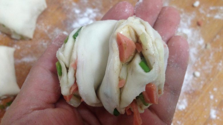 椒盐火腿葱香卷,两手握住面团的两头向相反的方向拧,然后把两头卷入底部,整理就好了