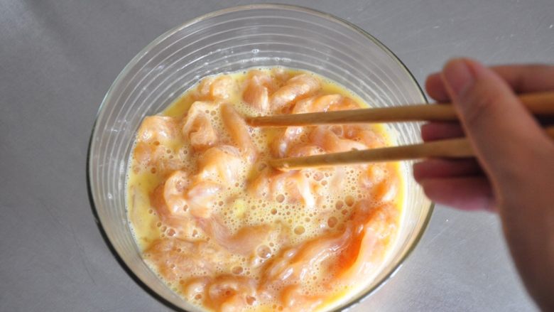 街头小吃自己做---香酥无骨鸡柳,将鸡肉倒入蛋液中,表面均匀的裹上蛋液。