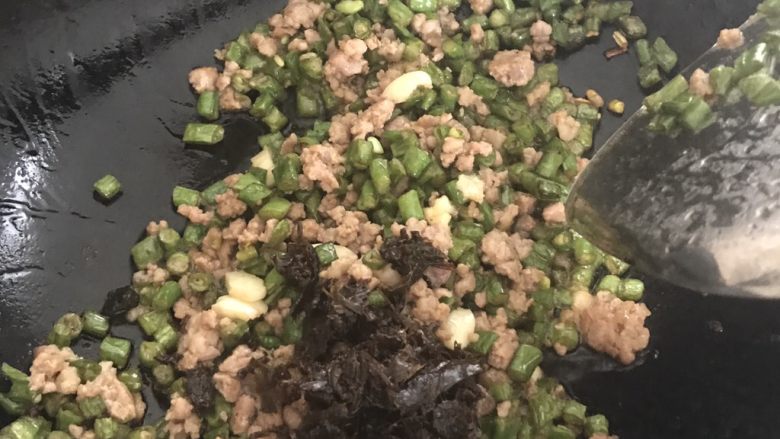 干煸橄榄肉沫豆角,再加入橄榄菜,尽量沥干油,等到橄榄菜炒香,加少许白糖