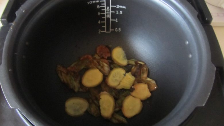 烤鸡(电饭煲版),将腌制的葱姜蒜部分垫入电饭煲的底部;