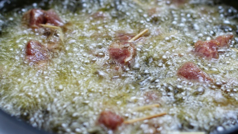牙签肉,锅中放适量油烧至八成热,放入肉串中火炸制