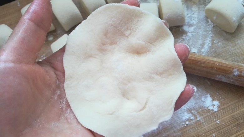 包菜馅素包子,把面皮托在手上,手指稍微弯曲形成面皮中间凹点,便于放馅料。