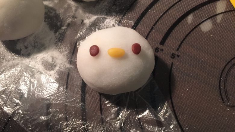 Kitty 冰皮月饼,把准备好的眼睛、嘴巴、胡须蘸上开水粘上,这个过程可以平放着粘