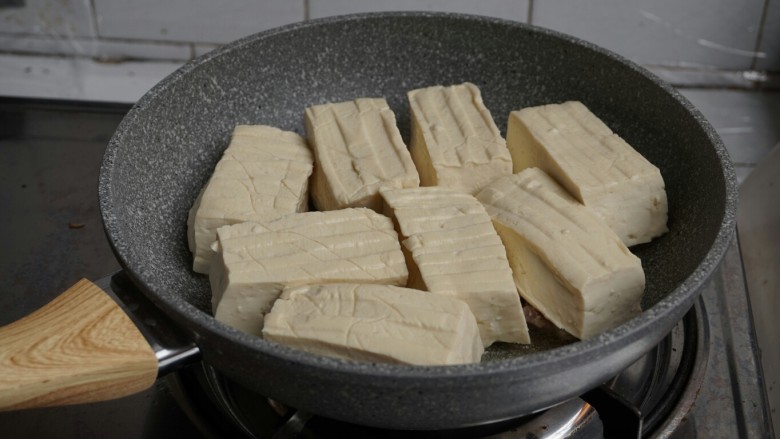 煎酿豆腐,转中火,将豆腐有馅的一面朝下,一块块放在锅里。