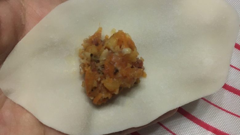 金鱼饺子,擀成椭圆形的面皮,尽量擀得薄一点,厚度和我们平时吃的水饺差不多。肉馅不要居中放在面皮上,尽量放在左边或右边一点,给等下捏的鱼尾留出相对的面皮。