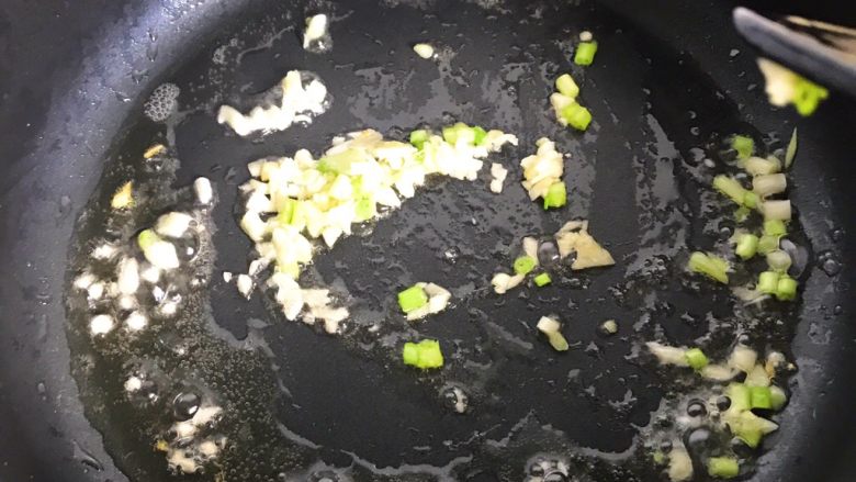 鸡蛋包菜炒年糕,锅里还有油的,就不用加了,放入蒜蓉和葱白翻炒,有香味溢出就可以,注意别炒焦了