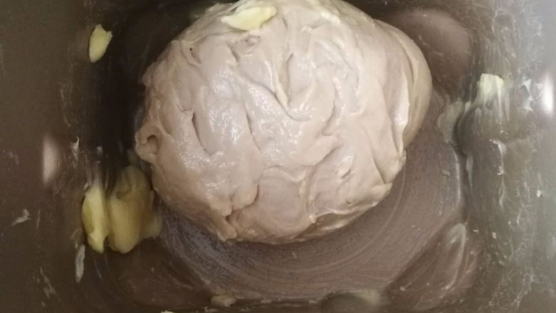 坚果软欧包(一次发酵),揉成光滑的面团后加入软化的黄油继续揉面。