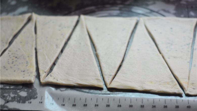 黑白芝麻可颂,将冷藏后的面团擀至4厘米厚,切割成底边为10厘米、高为25厘米的等腰三角形