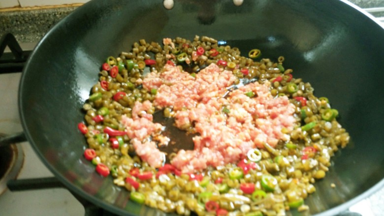 红油泡豇豆炒肉末,加入肉末，快递翻炒均匀后加入5克<a style='color:red;display:inline-block;' href='/shicai/ 717'>味精</a>翻炒均匀即可出锅。