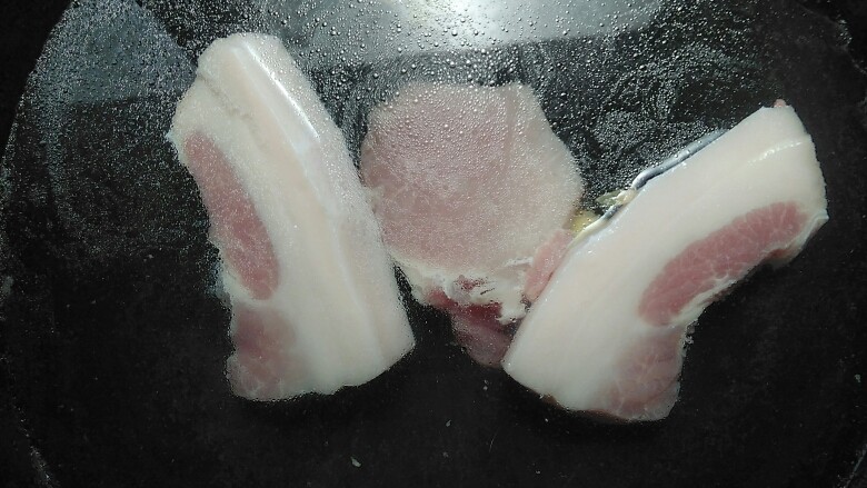 蒜香回锅肉,清洗干净后,锅中放入适量的清水,把肉肥瘦部分切开,然后放在锅中,加入<a style='color:red;display:inline-block;' href='/shicai/ 37'>姜</a>片,中火焯水3-4分钟左右