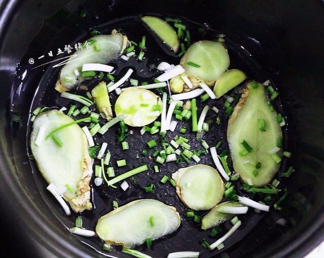 盐焗手撕鸡,在冰箱里腌制半天以上。鸡腌制好了,在电饭煲里倒两勺油,晃匀。姜切薄片,葱切段,和腌制用的葱姜一起,均匀在电饭锅底,铺满。
