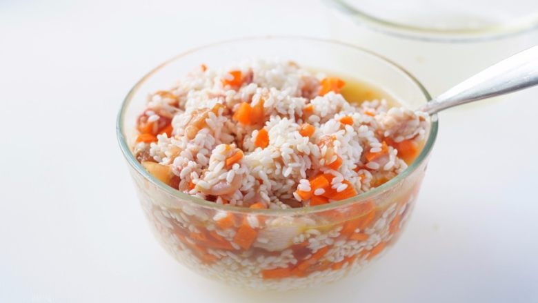 竹筒鸡肉米饭,挑出生姜,把腌渍好的鸡肉胡萝卜丁倒入盛有大米的容器里拌匀。