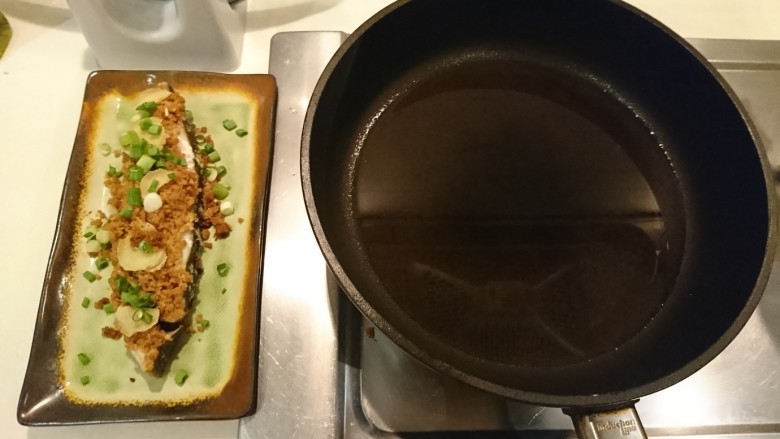 黑暗料理の豆酥鱈魚,在魚盤上撒蔥花，起油鍋把油加熱到很燙很燙到起煙