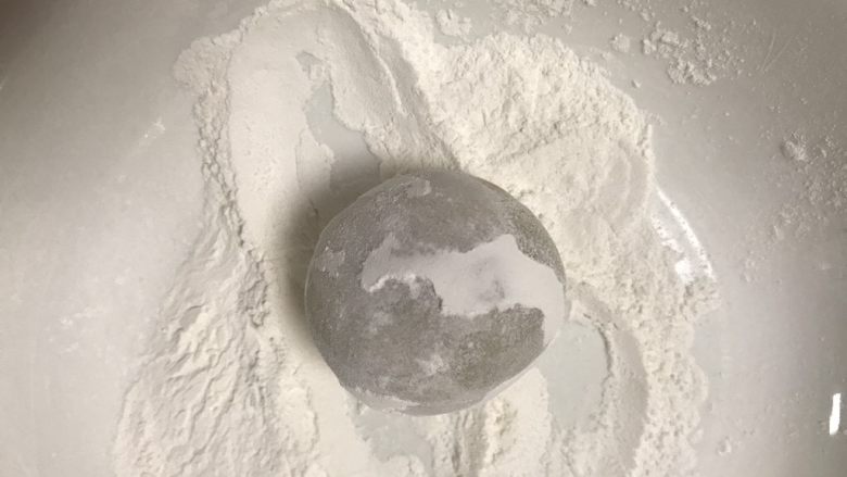 广式抹茶蛋黄月饼,取一个面团放在手粉里滚一下,用手搓掉多余的粉