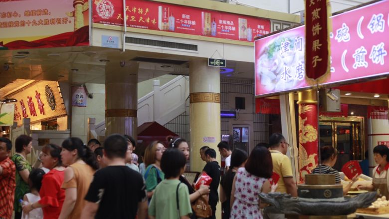 天津老味煎饼果子,天津南市食品街的煎饼果子摊一共有四个摊位,东西南北门各有一个摊位,这是游客们买煎饼果子排队的情景。