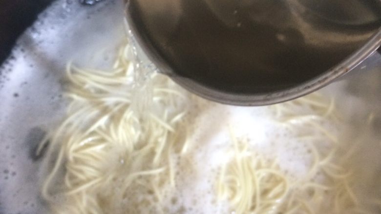 快手葱油面,看到许多白沫后,倒半碗凉水,再煮一分钟,放入之前准备的凉水中过一下,然后倒出凉水。