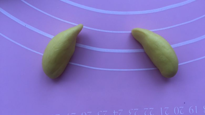 卡通狗狗馒头,取一个对半切开,搓成上尖下圆的小条。
