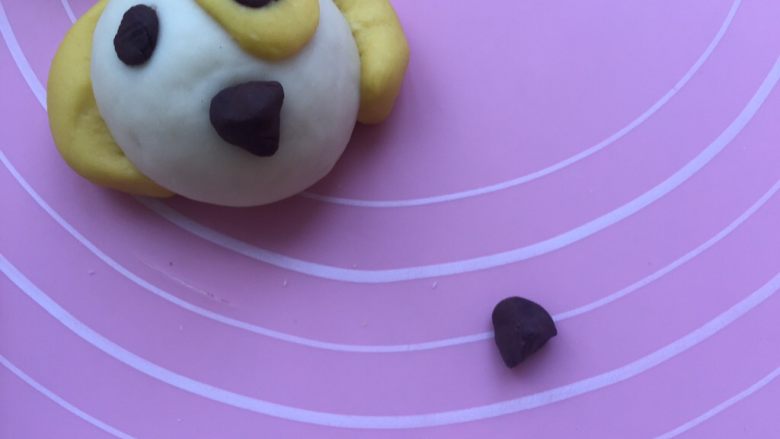卡通狗狗馒头,在取一点点可可面团做成立体的三角状,黏在狗狗的嘴巴处。