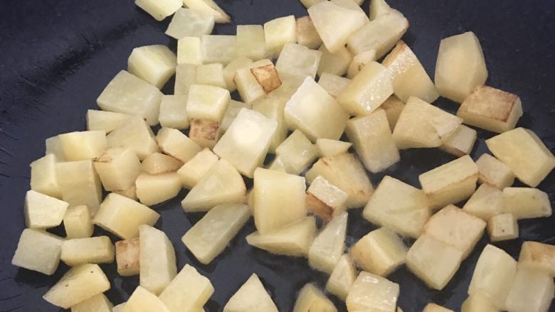 干煎土豆鸡丁,用锅铲翻开土豆底部,已经煎黄就可以翻一面