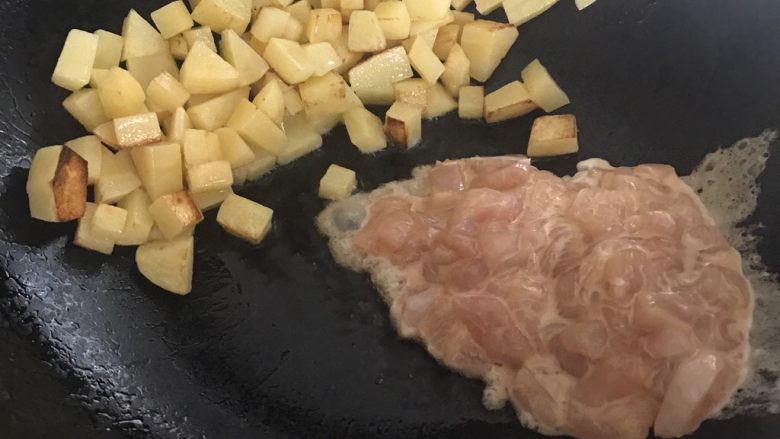 干煎土豆鸡丁,转中火,将土豆推到另一边,放入鸡丁,拌炒