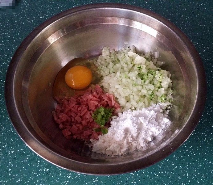 西瓜皮火腿鸡蛋饼,再将切好的西瓜皮碎丁挤去水份、与火腿丁一起放入小盆中、撒点葱花、打个鸡蛋、加入粉类