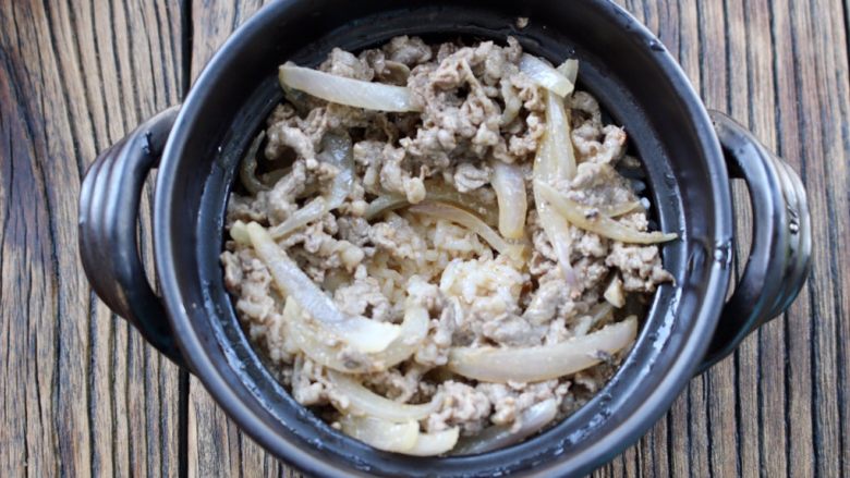 肥牛窝蛋砂锅,再放入肥牛洋葱,再把汤汁倒在米饭上,中间留一个蛋黄的空位