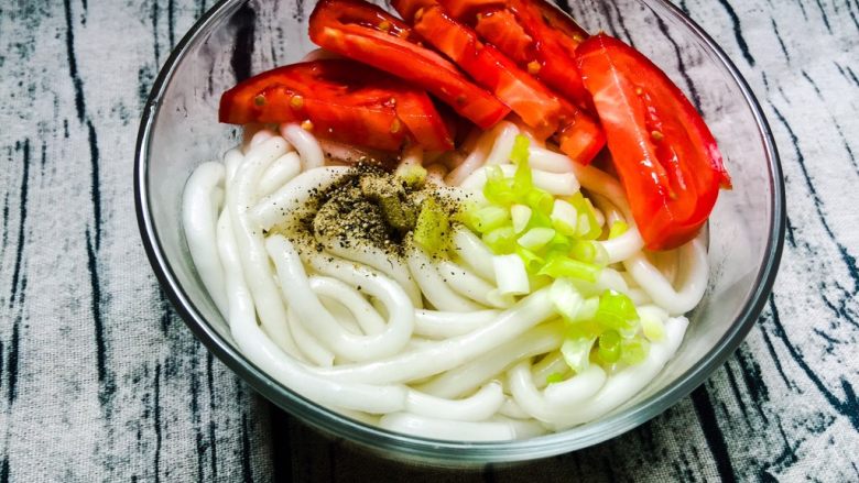 自制美味土豆粉,盛出摆盘,放入西红柿、小葱、胡椒粉