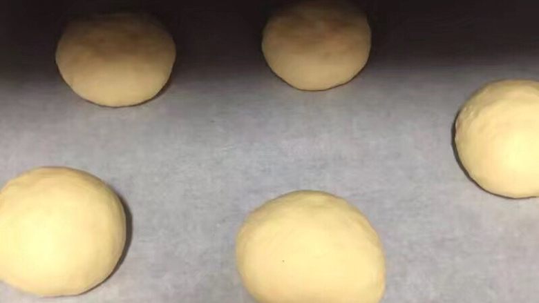 自制麦辣鸡腿汉堡,5个剂子揉至光滑,放入烤盘,如果不是不沾盘烤盘就铺上一张油纸,如图