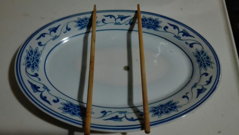 好想吃~清蒸鳊鱼,盘子上面放一双筷子,蒸鱼容易熟,蒸鱼的水滴到盘子里面,鱼和蒸鱼的水就不会在一起了