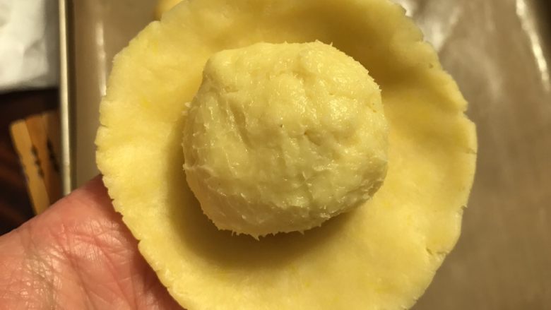 💋流心榴莲月饼🍥,拿出一份月饼皮压扁平后包入馅心, 封口必须要收紧。尽量不要让皮与馅之间出现空隙。
⚠️包好的月饼球先别急着印模,先盖上保鲜膜放回冰箱里冷藏醒面0.5-1小时。