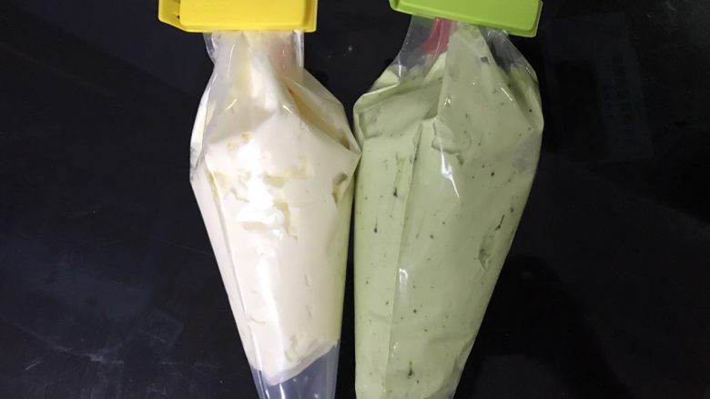 抹茶杯子蛋糕,取一般装入裱花袋,另一半倒入事先糊化好的抹茶糊搅拌均匀,装入裱花袋。