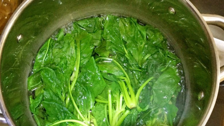 烟熏三文鱼菠菜蛋卷,在锅里放入水,烧滚后,放入菠菜,焯水2分钟左右,捞出放凉后,把水分挤干。