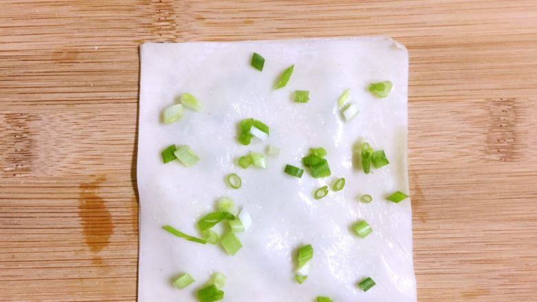 馄饨皮版香葱银丝饼,然后将第二张馄饨皮覆盖在第一张皮子上
用手掌轻轻按压,使其平整一些,然后重复涂油、撒盐、撒葱花的步骤