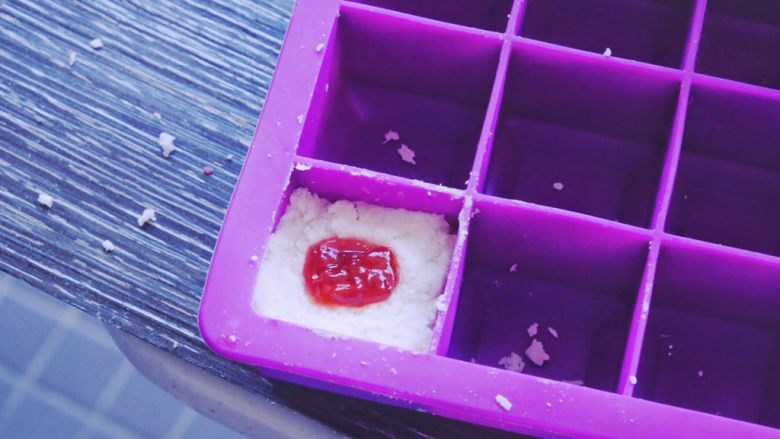 藏在每颗巧克力下的是不一样的内心,现在模具里压入一半椰子混合物 加入一勺果酱