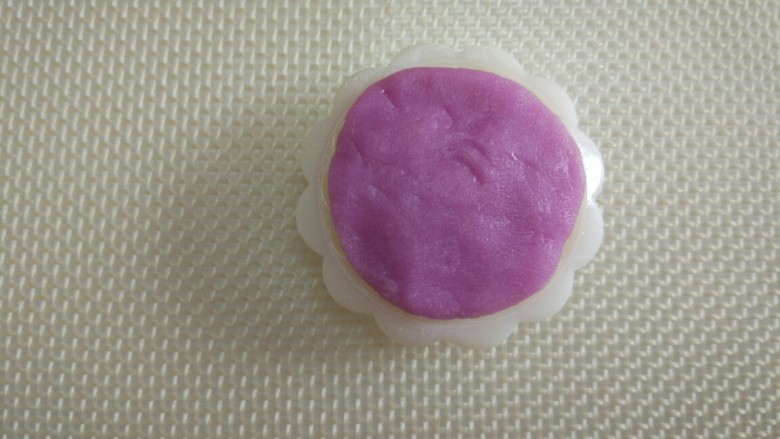 五彩冰皮月饼,取一个彩色面团,分割成两份,每个5克,揉成圆形,轻轻的按压在月饼模具的花片上,力度要均匀分布。(每种彩色面团是10克,每种颜色可以印出两个月饼)