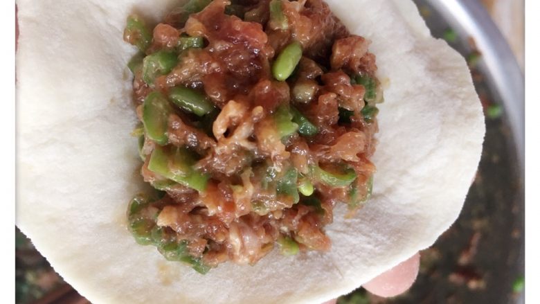 猪肉豆角包子,小剂子擀成圆片,放入肉馅包好