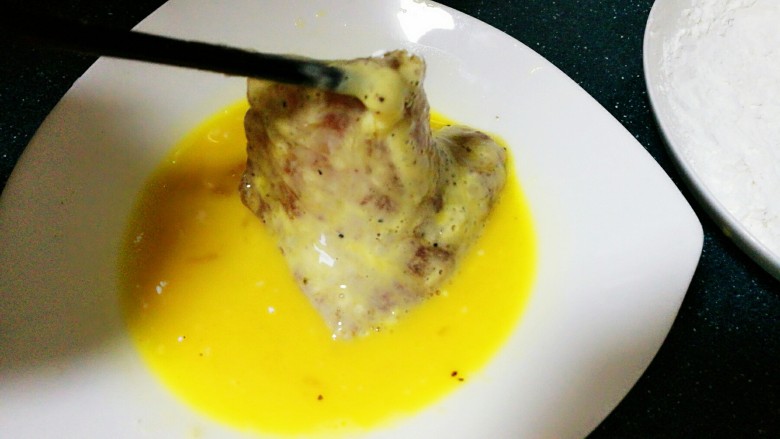 椒香猪排,将沾好淀粉的肉片再一次放入蛋液中,也是两面都沾上蛋液。