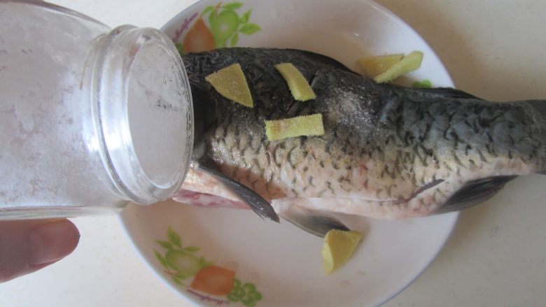鲫鱼豆腐汤,鲫鱼放入少许盐、姜片和料酒,涂抹均匀腌制一下;